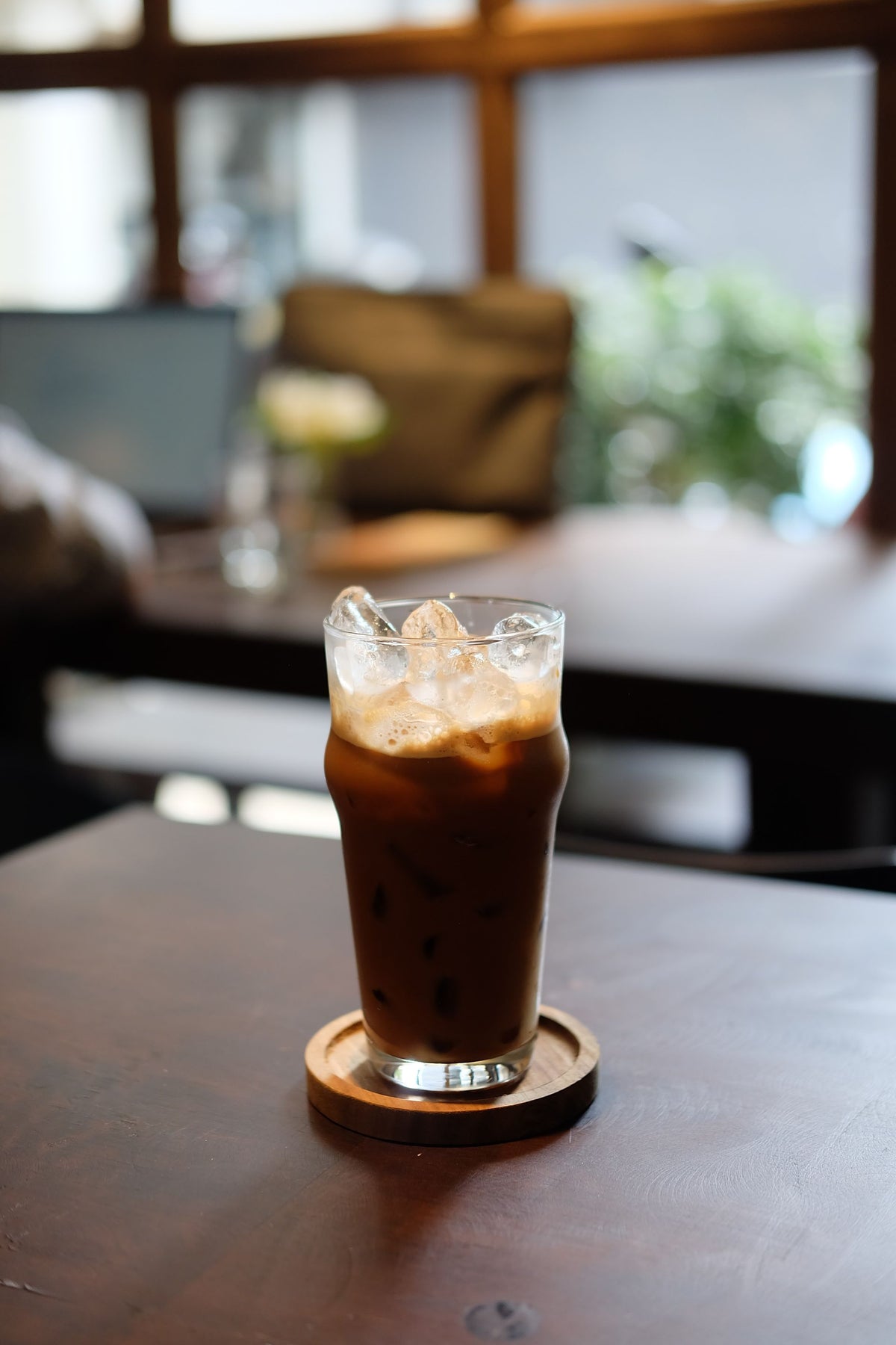 A refreshing glass of iced coffee served in a cozy indoor café environment.