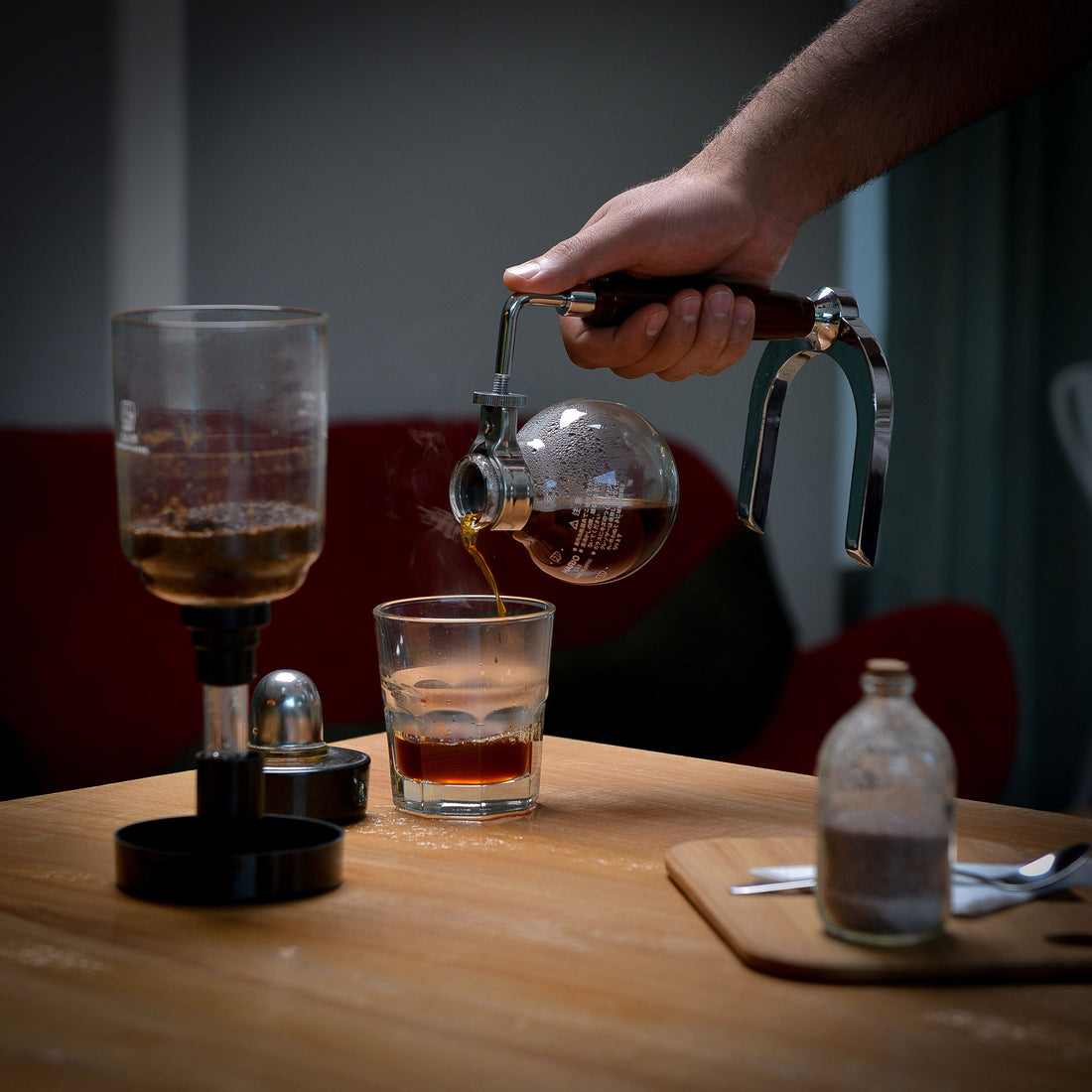 Coffee being poured from a French press into a glass on a table